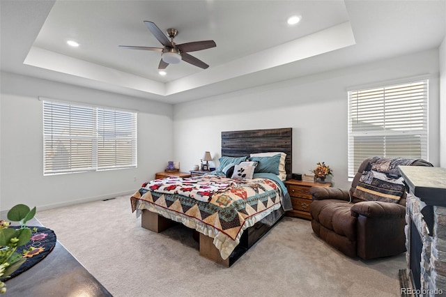 carpeted bedroom with ceiling fan and a tray ceiling