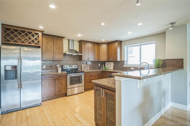 2539 N York St, Denver, CO 80205 - kitchen with stainless steel appliances, wall chimney exhaust hood, a peninsula, light wood-type flooring, and recessed lighting