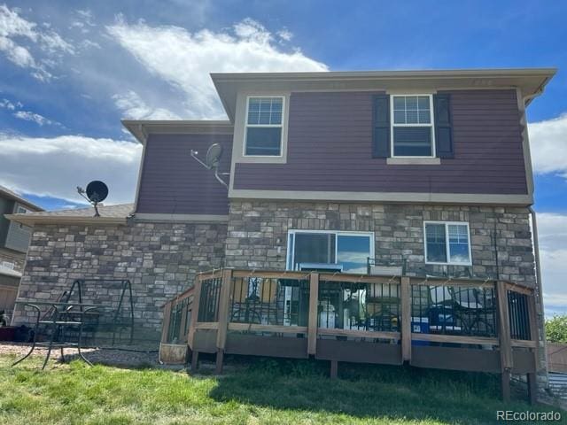 back of property with stone siding and a deck