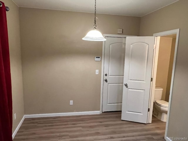 unfurnished dining area featuring baseboards and wood finished floors