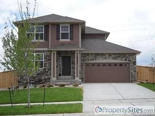 view of front of property with a front yard, fence, concrete driveway, stone siding, and a garage