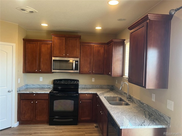 kitchen featuring a sink, visible vents, black appliances, and light wood finished floors