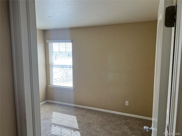 unfurnished room with a textured ceiling, baseboards, and carpet floors