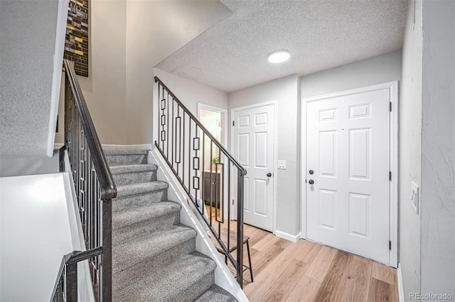 1470 S Quebec Way Unit 62, Denver, CO 80231 - entrance foyer featuring light wood finished floors, a textured ceiling, stairs, and baseboards
