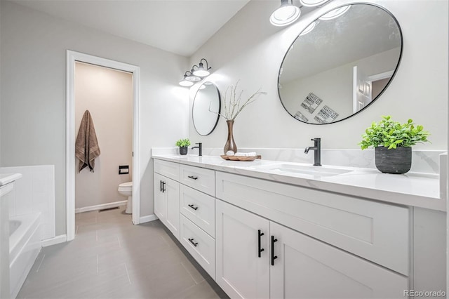 1470 S Quebec Way Unit 62, Denver, CO 80231 - bathroom featuring toilet, double vanity, tile patterned floors, a tub to relax in, and baseboards