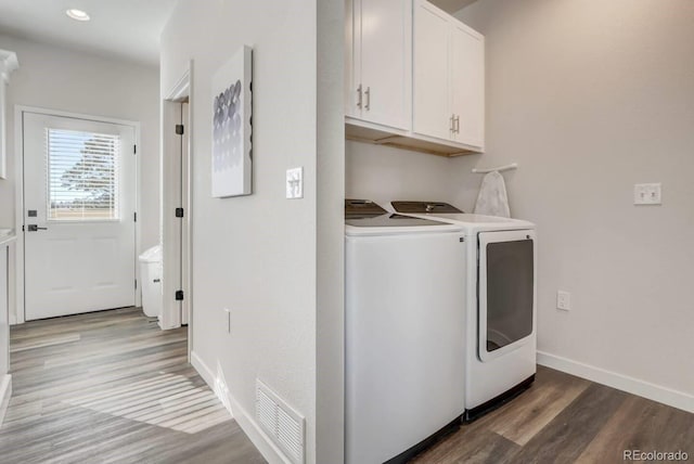 laundry room featuring washer and clothes dryer, cabinets, and hardwood / wood-style flooring