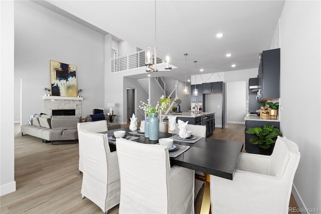 dining room with a towering ceiling, sink, and light hardwood / wood-style flooring