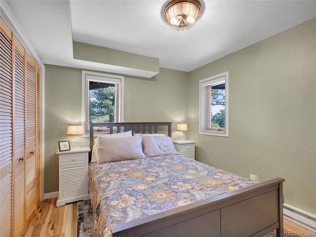 6574 Olympus Dr, Evergreen, CO 80439 - bedroom featuring light wood finished floors, a baseboard heating unit, a closet, and baseboards