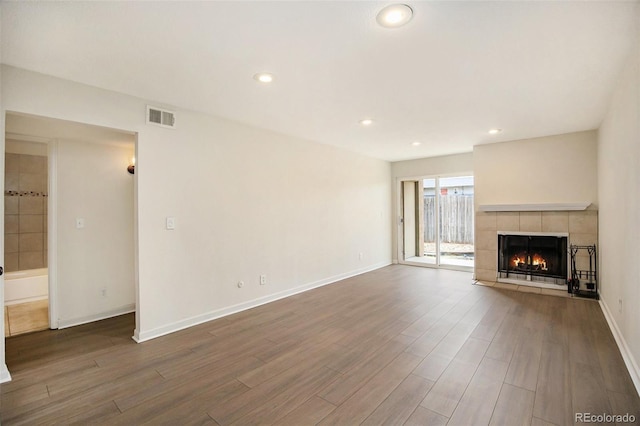 unfurnished living room featuring baseboards, a fireplace, visible vents, and wood finished floors