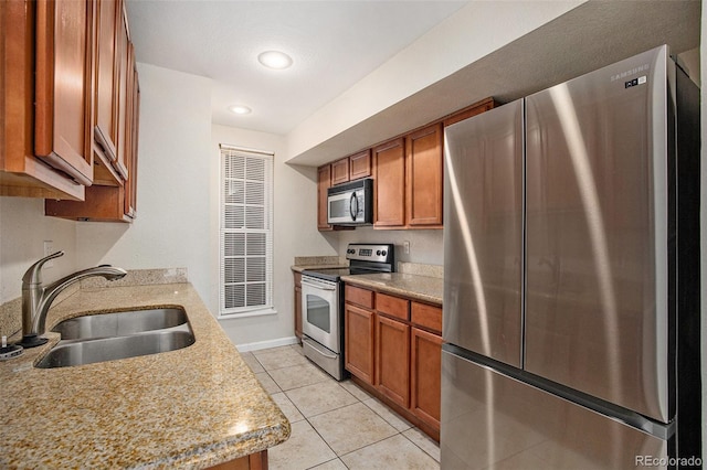 kitchen with light tile patterned floors, stainless steel appliances, brown cabinetry, and a sink