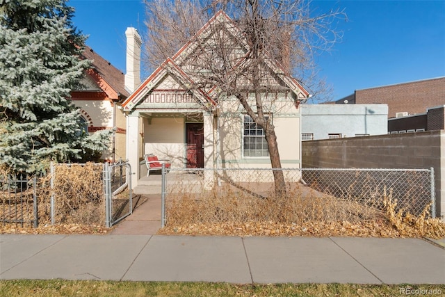 view of front of home with covered porch, a fenced front yard, and a gate