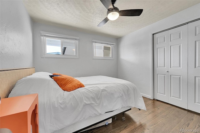 bedroom featuring multiple windows, light hardwood / wood-style floors, and a textured ceiling