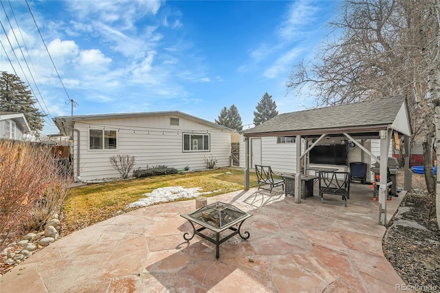 view of patio / terrace featuring a grill, an outbuilding, and a fire pit