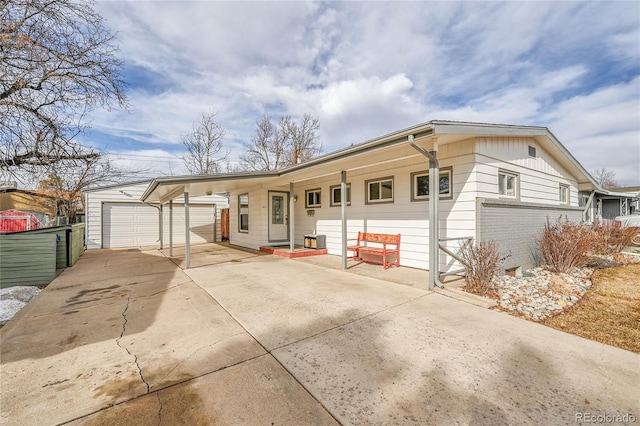 ranch-style home featuring a garage, a carport, and an outbuilding