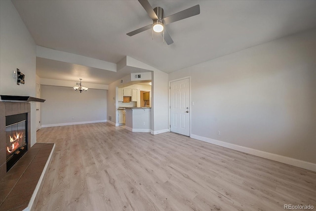 unfurnished living room with ceiling fan with notable chandelier, light hardwood / wood-style flooring, lofted ceiling, and a fireplace