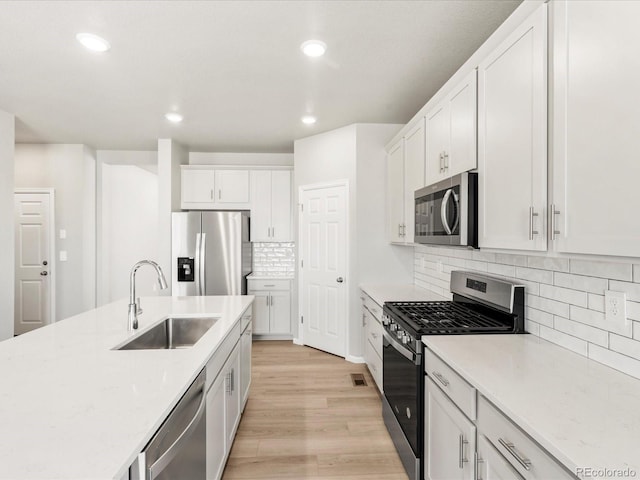 17487 E 89th Way, Commerce City, CO 80022 - kitchen with appliances with stainless steel finishes, a sink, white cabinetry, light wood-type flooring, and recessed lighting