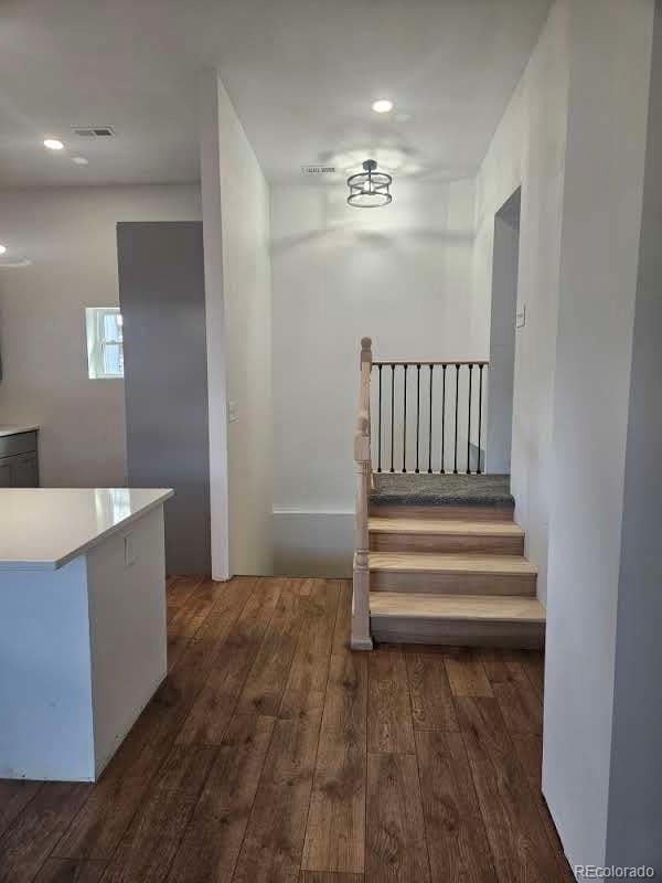 staircase with hardwood / wood-style floors, recessed lighting, and visible vents