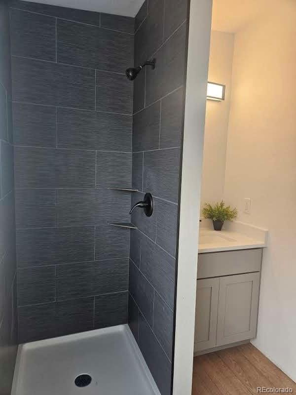 bathroom with a stall shower, vanity, and wood finished floors