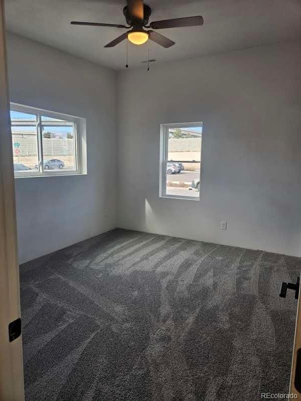 carpeted empty room with a ceiling fan