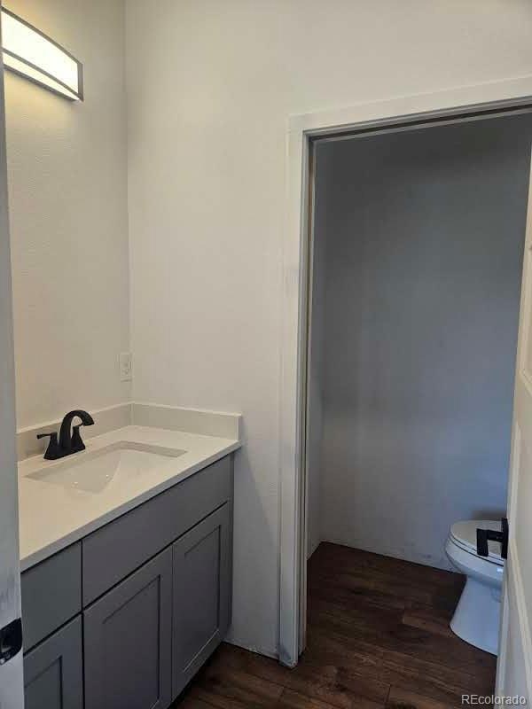 bathroom with toilet, wood finished floors, and vanity