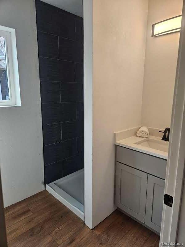 full bathroom with vanity, a shower stall, and wood finished floors