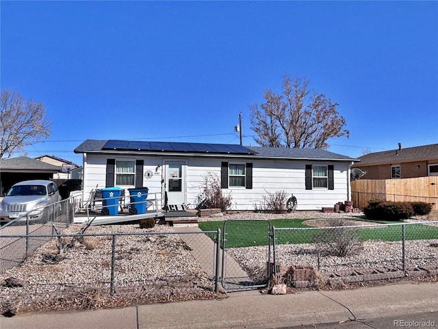 view of front of house with a fenced front yard, solar panels, and a gate