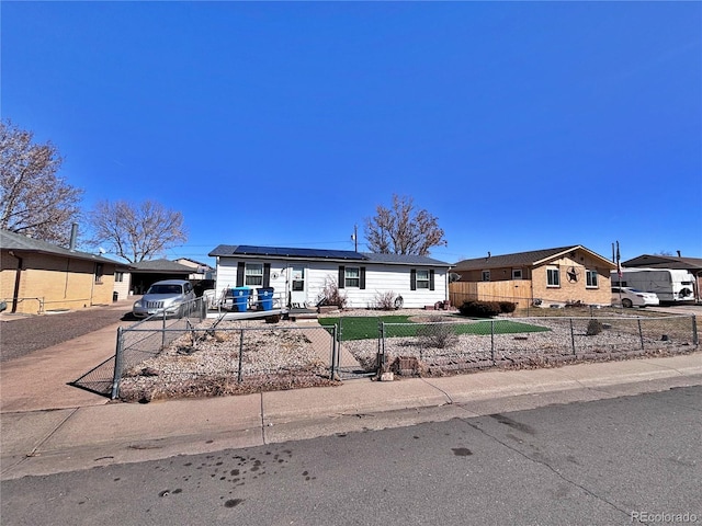 manufactured / mobile home featuring a fenced front yard, roof mounted solar panels, and driveway