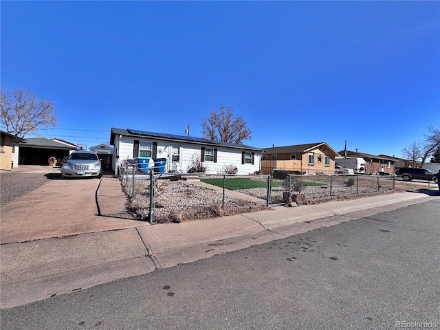 manufactured / mobile home featuring a fenced front yard, roof mounted solar panels, and concrete driveway