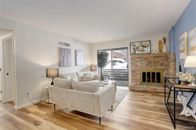 living area with light wood-type flooring, visible vents, a fireplace, and baseboards