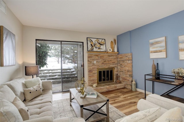 living area with light wood-type flooring, visible vents, a fireplace, and baseboards