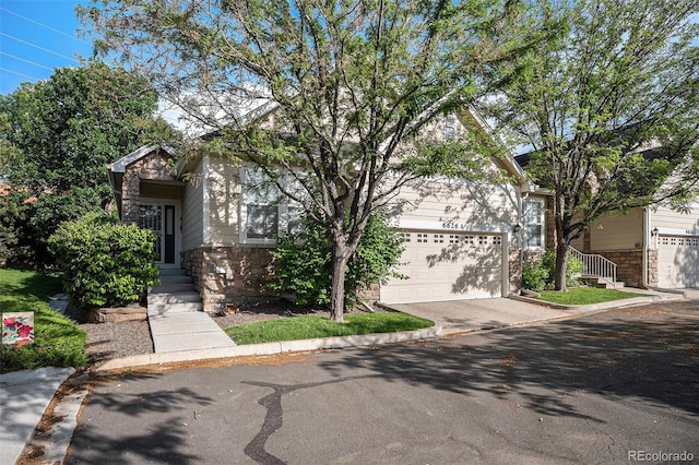 6626 S Reed Way Unit A, Littleton, CO 80123 - obstructed view of property with stone siding, driveway, and a garage