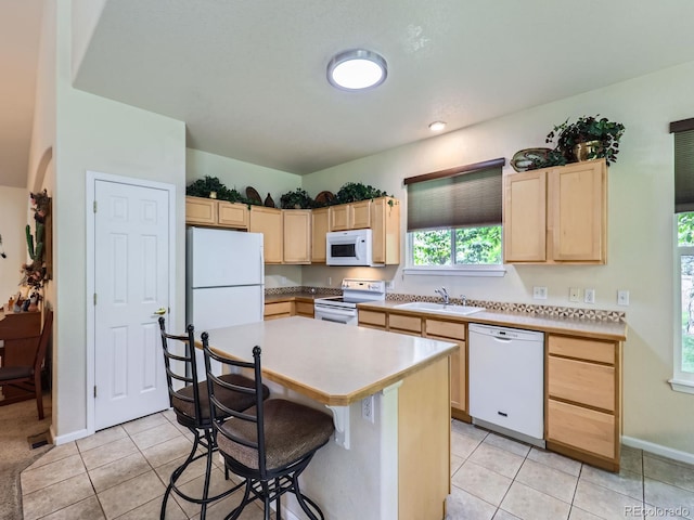 6626 S Reed Way Unit A, Littleton, CO 80123 - kitchen with white appliances, light brown cabinets, light tile patterned flooring, and a kitchen breakfast bar