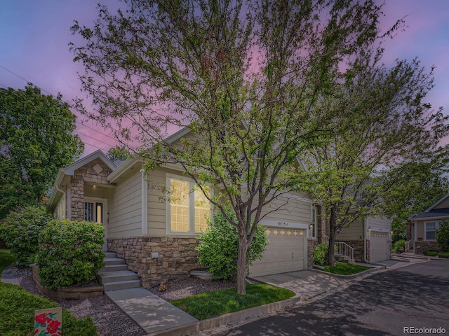 6626 S Reed Way Unit A, Littleton, CO 80123 - obstructed view of property featuring stone siding and concrete driveway