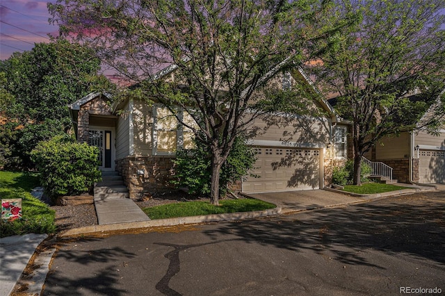 6626 S Reed Way Unit A, Littleton, CO 80123 - view of property hidden behind natural elements featuring stone siding, driveway, and a garage