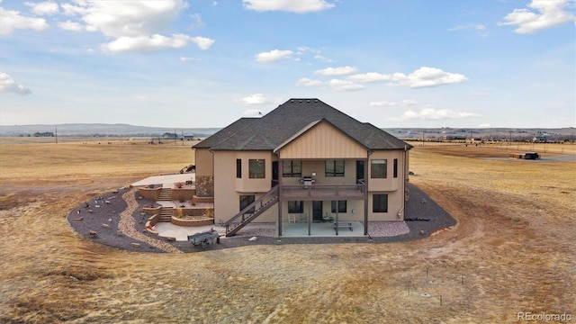 back of property featuring a patio, a mountain view, a yard, and a rural view