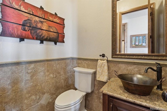 bathroom featuring vanity, toilet, and tile walls