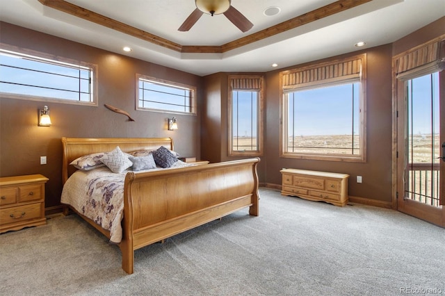 carpeted bedroom with a tray ceiling and ceiling fan