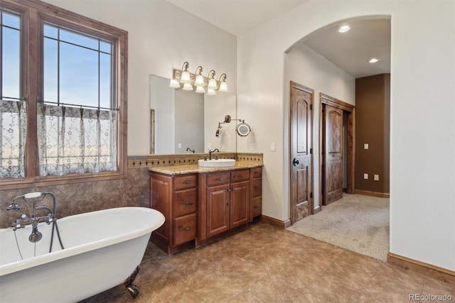 bathroom featuring vanity, tile walls, and a tub