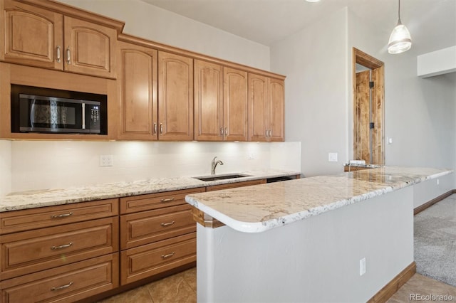 kitchen with sink, backsplash, a center island, light stone countertops, and decorative light fixtures