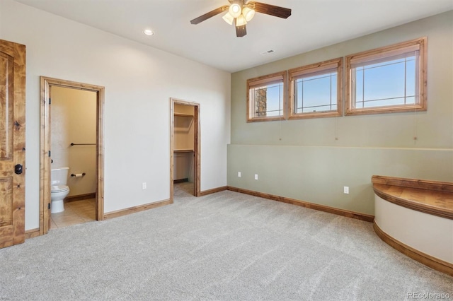 unfurnished bedroom with multiple windows, connected bathroom, a spacious closet, and light carpet