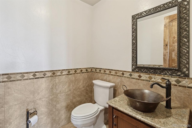 bathroom featuring vanity, tile walls, and toilet