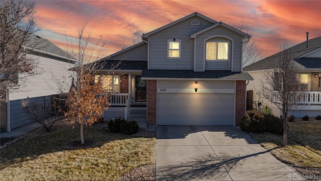 view of front facade featuring an attached garage, covered porch, concrete driveway, and brick siding