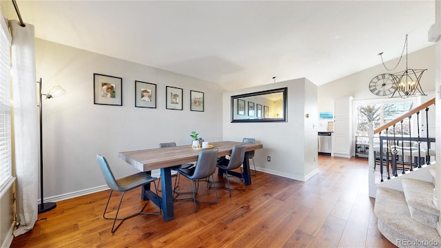 dining space featuring baseboards, stairway, wood finished floors, and a notable chandelier