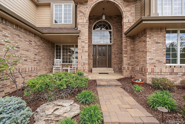 entrance to property featuring covered porch and brick siding