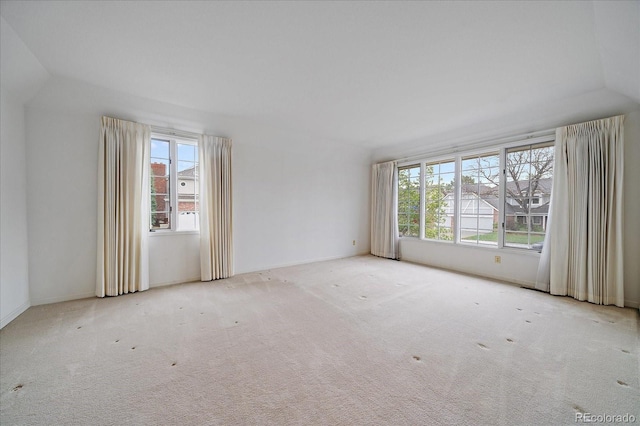 carpeted empty room featuring lofted ceiling and baseboards