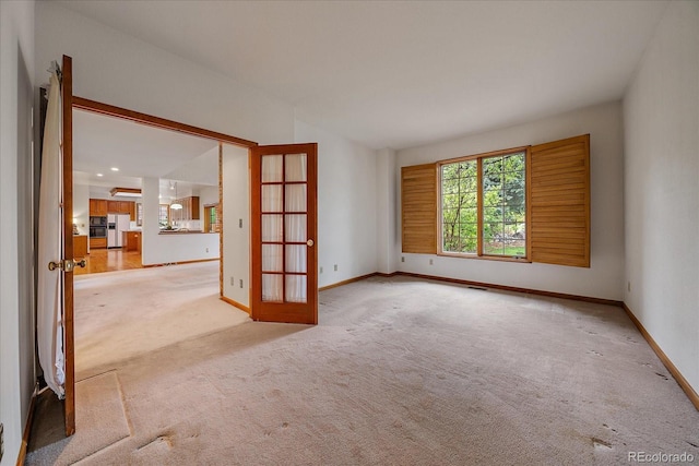 unfurnished room with light carpet, french doors, and baseboards