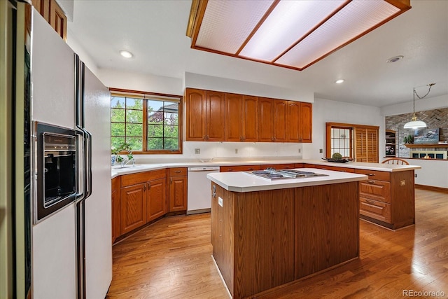 kitchen featuring white appliances, a center island, light countertops, light wood finished floors, and brown cabinets