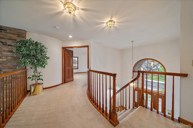 corridor featuring an upstairs landing, baseboards, and light carpet