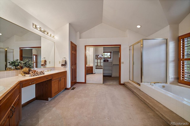 bathroom featuring vaulted ceiling, a shower stall, double vanity, tiled tub, and recessed lighting