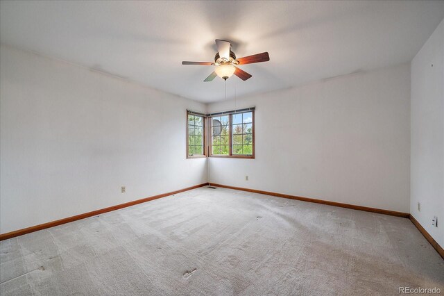 unfurnished room with carpet flooring, a ceiling fan, and baseboards